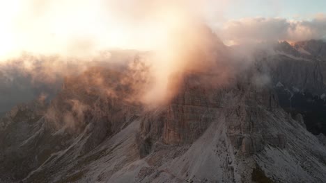 Clouds-surround-Mount-Averau-illuminated-by-sunset,-picturesque-Dolomites,-drone
