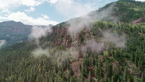 Drohnenansicht-Eines-Waldes,-Der-Durch-Wolken-In-Colorado-Auf-Bergen-Aufwächst