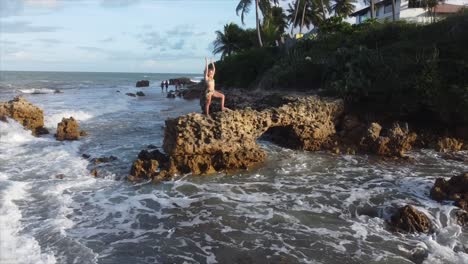 Girl-Standing-on-Rock-on-The-edge-of-Brazils-Ocean-Pan-out-to-Sunset