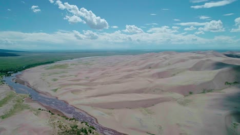 Drone-view-of-soft-sand-mountains-and-a-river-in-Colorado