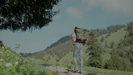 Backpacker-millennial-man-hiking-on-rural-countryside-dirt-path,-slow-motion