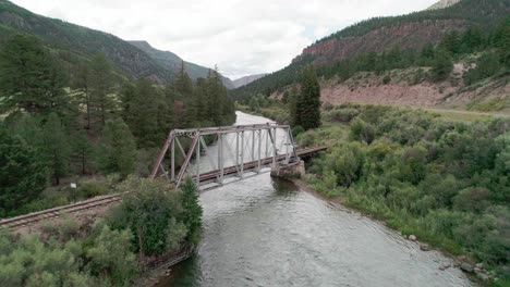 Drone-view-of-a-bridge-with-a-railroad-going-over-a-river-in-countryside-Colorado