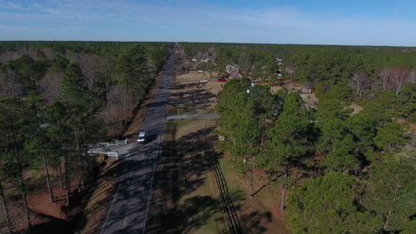 An-aerial-shot-moving-away-from-a-back-road-in-North-Carolina-while-a-few-cars-drive-down