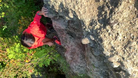Slowmo-vertical-video-of-sporty-older-woman-climbing-up-rocks