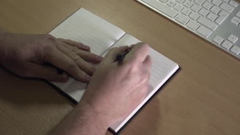 Schreiben-Einer-Aufgabenliste-Auf-Einem-Schreibtisch-Männliche-Hände