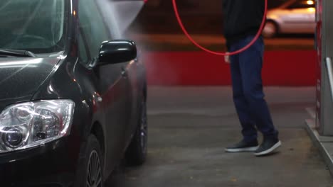 Man-on-manual-car-wash-at-night,-front-of-the-car
