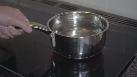 Saucepan-of-water-being-set-onto-an-electric-hob