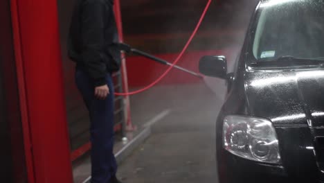 Man-on-manual-car-wash-at-night,-front-of-the-car