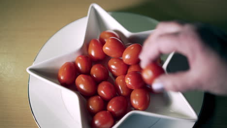 Tomatoes-in-shaped-star-dish-with-old-woman-hand-taking-one-delicately