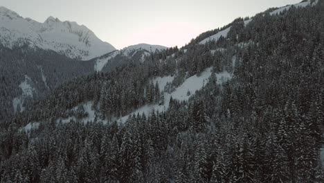 Drone-reveal-shot-of-sun-over-snowy-mountain-landscape-4k