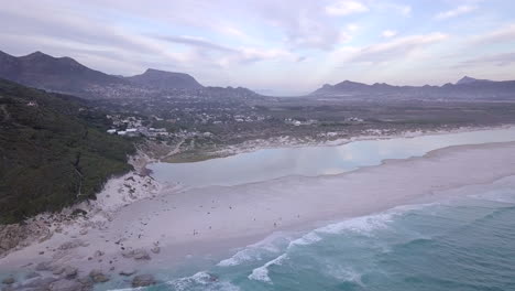 Aerial-footage-of-sea,-waves-and-town-near-beach-in-South-Africa,-Cape-Town,-Noordhoek