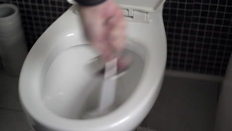 Die-Hand-Des-Mannes-Schrubbt-Eine-Weiße-Toilettenschüssel-Mit-Einer-Toilettenbürste