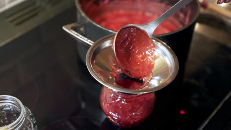Homemade-jam-being-poured-into-pots-stainless-steel-funnel-and-ladle
