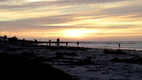 Männer,-Die-Bei-Sonnenuntergang-Am-Strand-Fischen