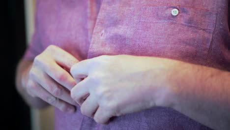 Man-with-parkinson's-disease-shakes-hands-trying-to-button-shirt,-frustrated