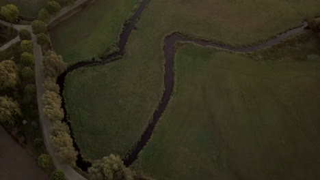 birds-eye-view-of-a-little-stream-in-a-field-during-sunrise