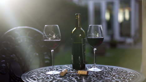 Eine-Flasche-Rotwein-Und-Zwei-Gläser-Sitzen-Auf-Dem-Gartentisch-Wintergarten