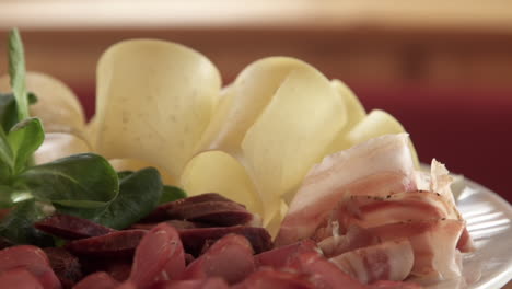 Schweizer-Gericht-Mit-Rasierten-Stücken-Von-Luftgetrocknetem-Fleisch,-Speck,-Schinken-Und-Käse-Auf-Rotierender-Platte