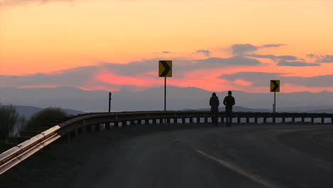 Ein-Paar-Am-Rand-Einer-Autobahn,-Das-Den-Sonnenuntergang-Beobachtet