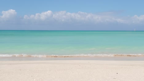 Una-Hermosa-Playa-Con-Agua-Turquesa-Y-Pequeñas-Olas-Y-Cielo-Azul