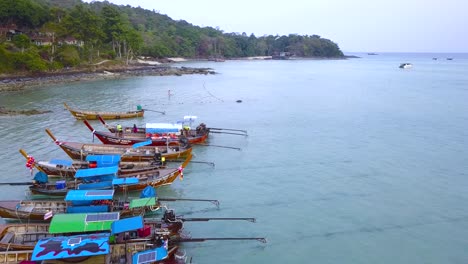 4K-AERIAL-FORWARD-VIEW-of-Long-boats-moored-in-Phi-Phi-Island-bay,-Phi-Phi-Don,-Thailand