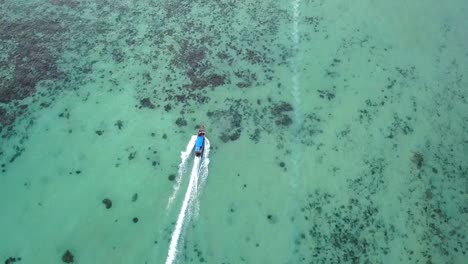 Drone-chasing-long-tail-boat-in-a-turquoise-water-and-crystal-clear-sea,4k-View-from-above,-stunning-aerial-shot-from-Phi-Phi-Islands,-Thailand,-surrounding-by-water