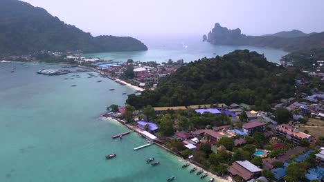 4K-AERIAL-DOLLY-BACKWARD-VIEW-of-Phi-Phi-Don-village-and-Ao-Tonsai-Pier,-incredible-rock-cliff-in-Thailand,-surrounding-water-bay