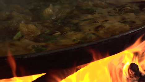 Slow-Motion-of-Authentic-and-Traditional-Spanish-Paella-Cooking-with-Fiery-Firewood-in-Barraca,-Valencia