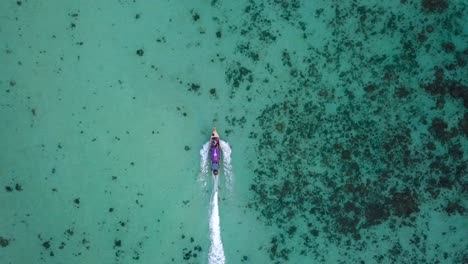 4k-View-from-above,-stunning-approach-aerial-view-of-a-traditional-long-tail-boat-sailing-on-a-beautiful-turquoise-and-clear-sea,Phi-Phi-Islands,-Thailand