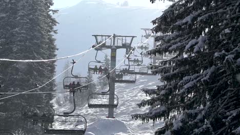 Chairlifts-In-Operation-While-Snow-Falls-From-Trees