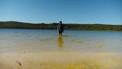 male-tourist-walking-into-the-brown-lake,-north-stradbroke-island,-Queensland,-Australia