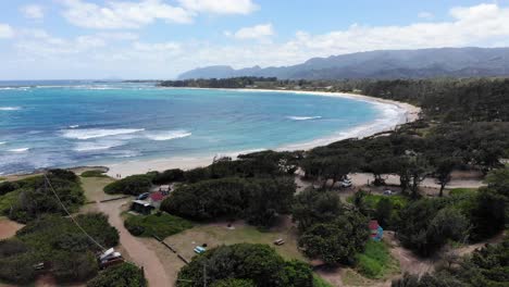 Slowly-descending-aerial-drone-shot-of-a-beachfront-campsite-in-the-Pacific-Region,-Hawaii,-North-Shore