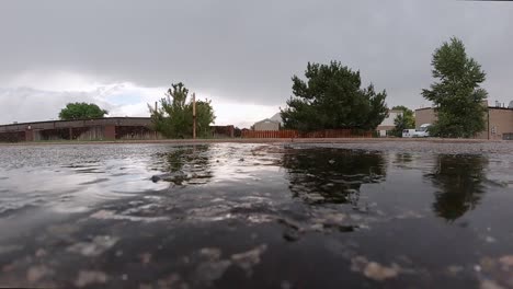 Raindrops-hitting-a-puddle-in-an-asphalt-driveway-in-slow-motion
