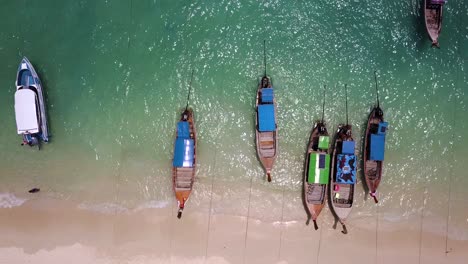 4k-Luftaufnahme-Von-Langen-Booten,-Die-Am-Strand-Festgemacht-Sind,-Phi-Phi-Don,-Thailand