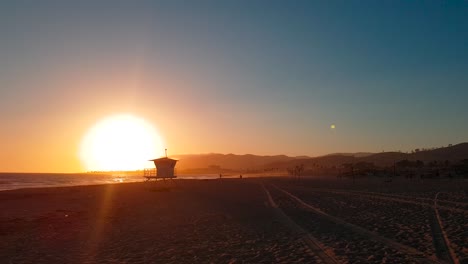 Slow-panoramic-sunset-shot-of-San-Buenaventura-State-Beach-with-Lifeguard-house-:-tower-in-Ventura,-California,-United-States