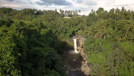 AERIAL-TILT-DOWN-OVER-WATERFALL-of-BALI-,-Tegenungan-Waterfall,-Indonesia,-with-surrounding-forest