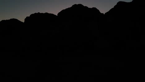 Langsamer-Schuss,-Der-über-Felsen-Aufsteigt-Und-Sonnenuntergang-Mit-Silhouetten-Von-Menschen-Am-Ufer-Am-San-Buenaventura-State-Beach-In-Ventura,-Kalifornien,-Vereinigte-Staaten-Enthüllt