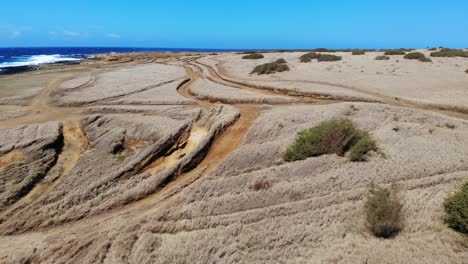 Volcanic-coastal-landscape-and-grassland---aerial-drone-shot-4k-moving-forward-over-wrecked-cars