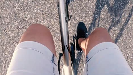 POV-footage-of-male-legs-cycling-on-a-bike-while-driving-on-a-asphalt-way,-in-Full-HD