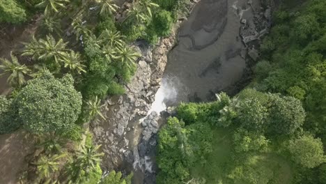 AERIAL-Spiraling-overhead-view,-Drone-descending-over-waterfall-in-Bali,-Indonesia