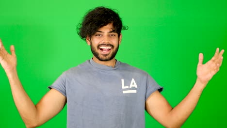 Indian-guy-showing-up-and-saying-hello-to-the-camera-with-waving-hand-with-green-background---green-screen