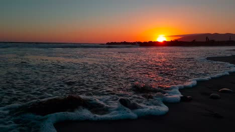 Low-gimbal-shot-of-beach-at-sunset-showing-close-up-of-waves-crashing-at-San-Buenaventura-State-Beach-in-Ventura,-California,-United-States
