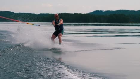 Slowmotion-closeup-of-a-young-man-riding-a-wakeboard-after-a-sport-boat-in-the-Swedish-archipelago-in-the-summer