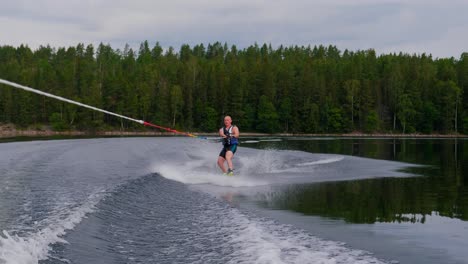 Slowmotion-over-a-young-man-riding-a-wakeboard-after-a-sport-boat-in-the-Swedish-archipelago-in-the-summer-sub3