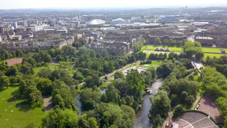 Drone-flying-over-Glasgow-Skyline-with-park-in-foreground