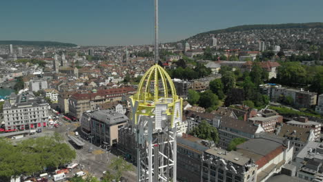 Close-aerial-drone-shot-orbiting-around-and-rising-up-amusement-park-free-fall-tower-in-Zürich,-Switzerland-during-Zürichfest