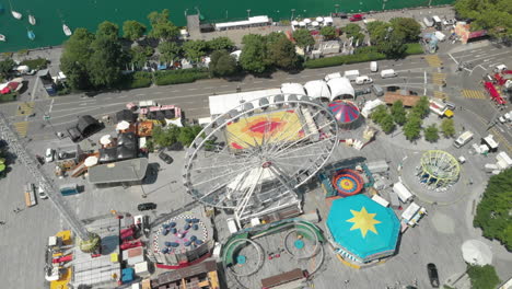 Beautiful-orbiting-aerial-drone-shot-flying-down-and-around-amusement-park-ferris-wheel-with-the-city-of-Zürich,-Switzerland-in-the-background-during-Zürichfest