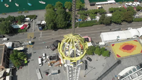 Aerial-drone-shot-flying-down-while-orbiting-around-and-coming-very-close-to-amusement-park-free-fall-tower-in-Zürich,-Switzerland-during-Zürichfest