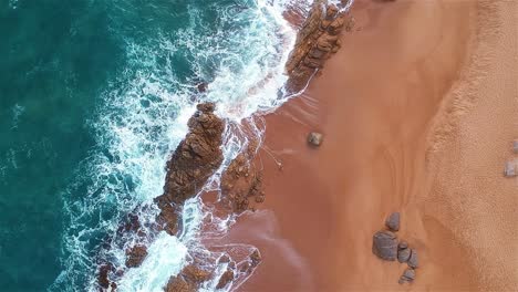 Stationary-Aerial-top-shot-of-a-coastline-where-the-ocean-meets-the-shore
