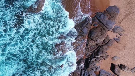 Aerial-top-shot-of-a-coastline-where-the-ocean-meets-the-shore-slow